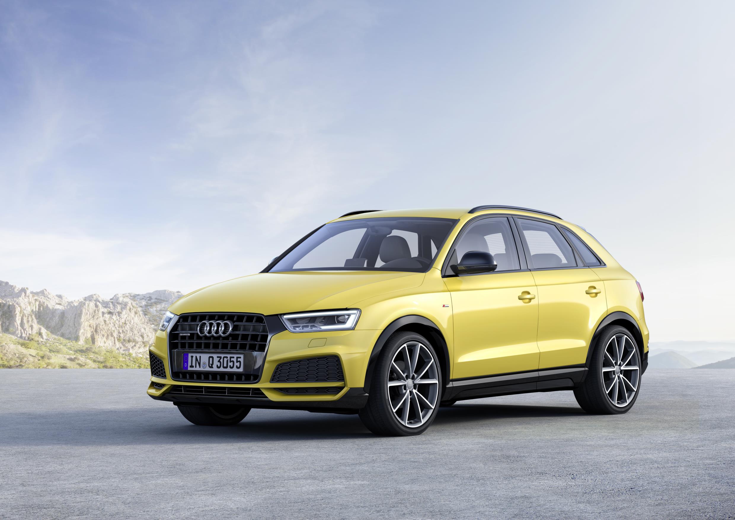 Yellow Audi Q3 parked facing left, overlooking a mountain range.